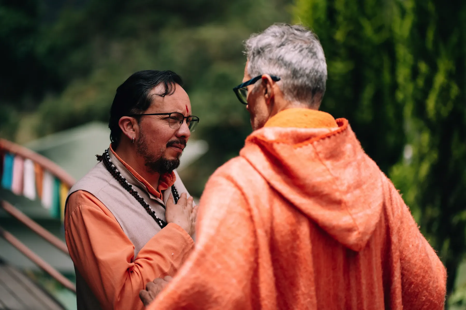 Dos personas conversan al aire libre, una de ellas con capucha naranja